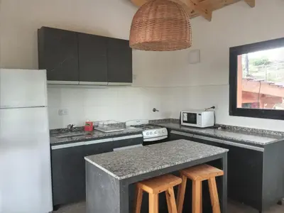 a kitchen with a white refrigerator and a counter with stools at Cabañas Aldea Lucerna La Cumbrecita in La Cumbrecita
