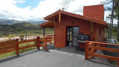 a small wooden cabin with a grill on a deck at Cabañas Aldea Lucerna La Cumbrecita in La Cumbrecita