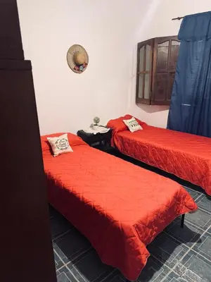 two beds with red sheets in a room at Casa Cento in Santa Rosa de Calamuchita