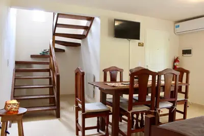 a dining room with a table and chairs and a staircase at Amaneciendo cabañas in Merlo