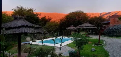 a swimming pool with umbrellas and a mountain in the background at Amaneciendo cabañas in Merlo