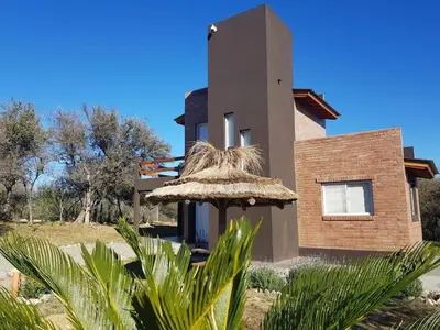 a house with a straw umbrella in front of it at Amaneciendo cabañas in Merlo