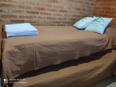 a bed with two pillows and a brick wall at Don Sabino in Arroyo de Los Patos