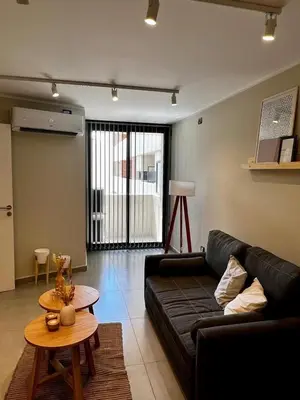 a living room with a black couch and a table at Lima 1300 B General Paz in Cordoba
