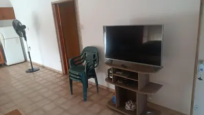 a living room with a television and a green chair at Casa Ayeya in Villa Carlos Paz