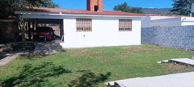 a white house with a garage and a yard at Casa Ayeya in Villa Carlos Paz
