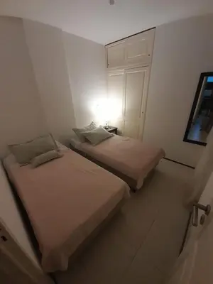 two beds in a white room with a light on at Departamento a metros peatonal Carlos Paz in Villa Carlos Paz