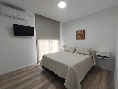 a white bedroom with a bed and a flat screen tv at Sam 1 Sampaoli in Villa Carlos Paz