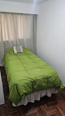 a green bed in a room with a window at Apartamento en Nueva Córdoba in Cordoba