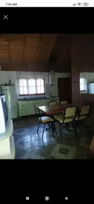 a room with a table and chairs and a kitchen at Cabaña con piscina compartida in Mina Clavero