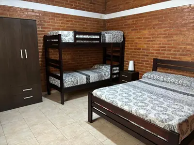 a bedroom with two bunk beds and a brick wall at Cabañas AdamiS 2 in Villa Cura Brochero