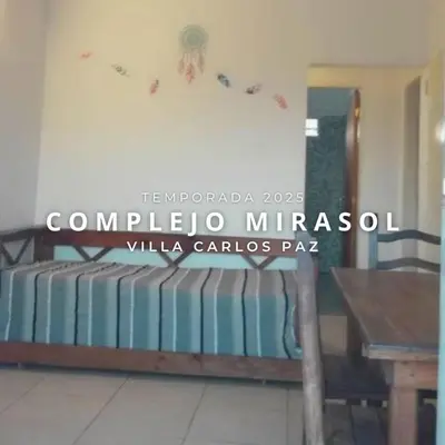 a room with two beds and a wooden table at Complejo Mirasol en Carlos Paz in Villa Carlos Paz