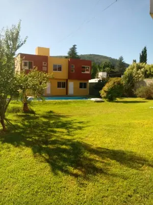 a house in the middle of a grassy field at Duplex en complejo in Villa Carlos Paz