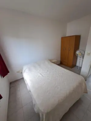 a bedroom with a white bed and a wooden cabinet at Duplex en complejo in Villa Carlos Paz