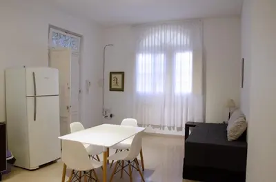 a white kitchen with a white table and a white refrigerator at Amplio departamento de un dormitorio a 15 min del centro de la ciudad in Cordoba