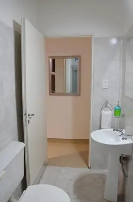 a white bathroom with a sink and a mirror at Amplio departamento de un dormitorio a 15 min del centro de la ciudad in Cordoba