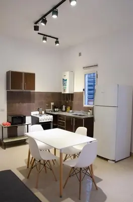a kitchen with a table and chairs and a white refrigerator at Amplio departamento de un dormitorio a 15 min del centro de la ciudad in Cordoba