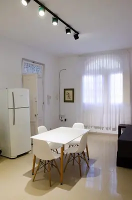 a white table and chairs in a room with a refrigerator at Amplio departamento de un dormitorio a 15 min del centro de la ciudad in Cordoba