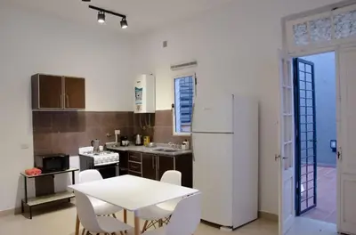 a kitchen with a white table and a white refrigerator at Amplio departamento de un dormitorio a 15 min del centro de la ciudad in Cordoba