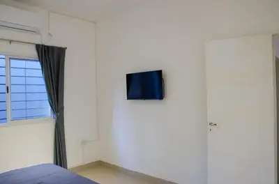 a bedroom with a tv on the wall next to a window at Amplio departamento de un dormitorio a 15 min del centro de la ciudad in Cordoba