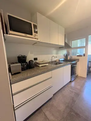 a kitchen with white cabinets and a microwave at Departamento Córdoba IV, estadio Kempes, Siglo 21,Cerro de las Rosas, Chateau in Cordoba
