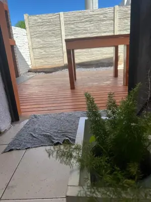 a wooden deck with a table and a rug at La Petrona in Alta Gracia