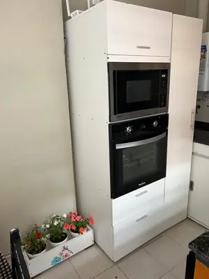 a white cabinet with a microwave and some plants at La Petrona in Alta Gracia