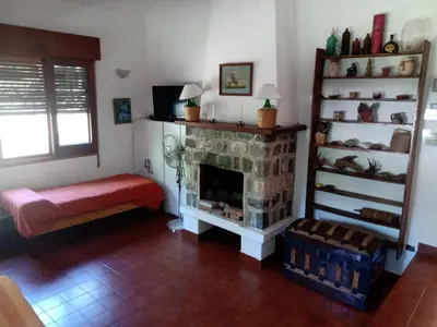 a living room with a stone fireplace and a bench at Casa Ortiz in Villa Canada del Sauce