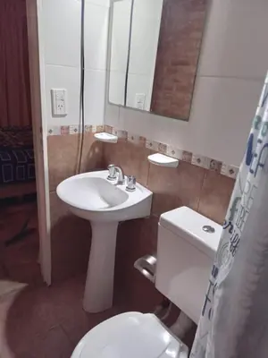 a bathroom with a sink and a toilet and a mirror at Monoambiente con piscina compartida in Mina Clavero