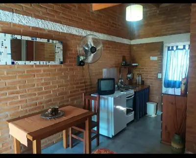 a kitchen with a white refrigerator and a small table at Monoambiente con piscina compartida in Mina Clavero