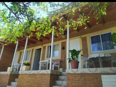 a yellow house with a porch with chairs on it at Monoambiente con piscina compartida in Mina Clavero