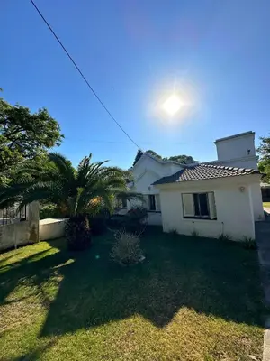 a white house with a palm tree in the yard at El GOLF in Alta Gracia