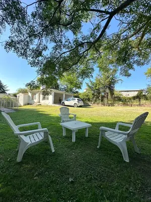 three white chairs and a table in the grass at El GOLF in Alta Gracia