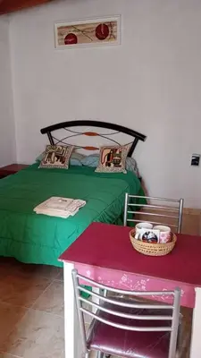 a bedroom with a green bed and a table at Rincón de las Calandrias Embalse in Embalse
