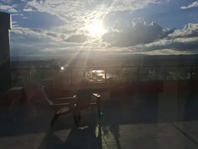 a person sitting in a chair on a balcony with the sun at Departamento Miralejos 16 in Villa Carlos Paz