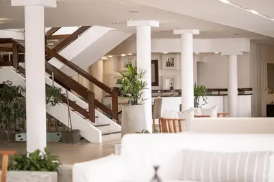a lobby with white tables and chairs and stairs at Santa Cecilia Resort & Spa I in Villa Carlos Paz
