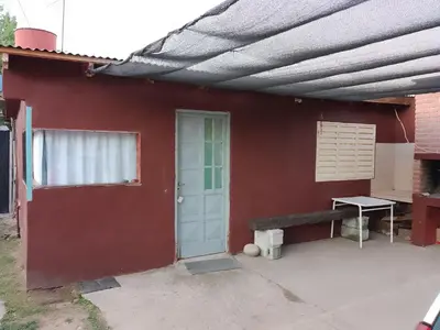 a red house with a blue door and a bench at Dpto Bordo in Villa Cura Brochero