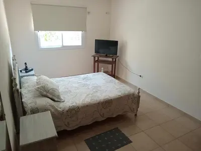 a small bedroom with a bed and a television at Casa verde - cerca Hospital Privado y Quality in Cordoba