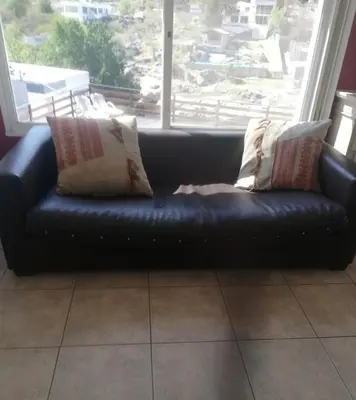 a black leather couch sitting in front of a window at Alquiler Temporal desde febrero in Villa Carlos Paz
