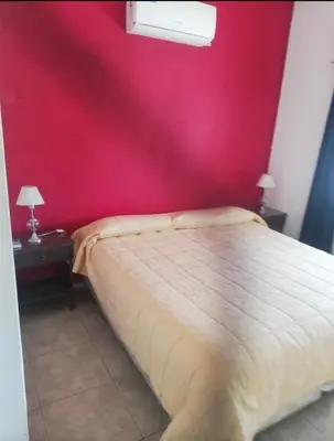a bedroom with a red wall and a bed at Alquiler Temporal desde febrero in Villa Carlos Paz