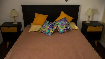 a bed with four pillows on it with two lamps at Lugones Park View in Cordoba