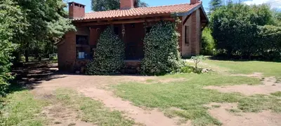 a brick house with two trees in front of it at Cabaña Inti Huafi in Arroyo de Los Patos