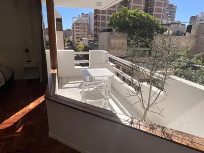 a balcony with a table and a tree on a building at Departamento Orange - Piso 3 Laprida Once in Cordoba