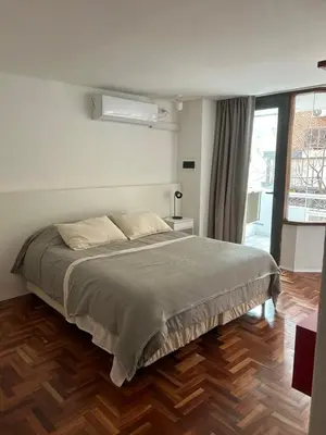 a bedroom with a large bed and a wooden floor at Departamento Red - Piso 2 Laprida Once in Cordoba