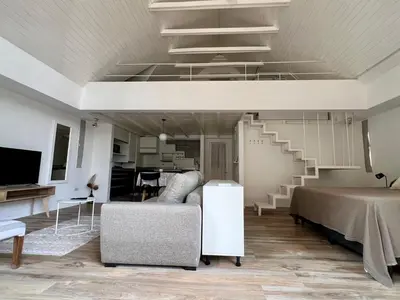 a living room with a couch and a staircase at Departamento Duplex - Piso 4 Laprida Once in Cordoba