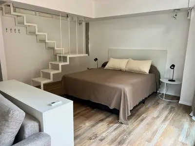 a bedroom with a bed and a spiral staircase at Departamento Duplex - Piso 4 Laprida Once in Cordoba