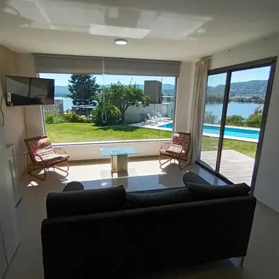 a living room with a couch and a large window at Casa en Villa Carlos Paz con pileta y vista al Lago IG alquilervillacarlospaz in Villa Carlos Paz