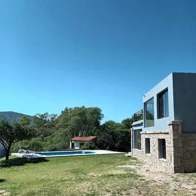 a house with a swimming pool next to a building at Casa en Villa Carlos Paz con pileta y vista al Lago IG alquilervillacarlospaz in Villa Carlos Paz