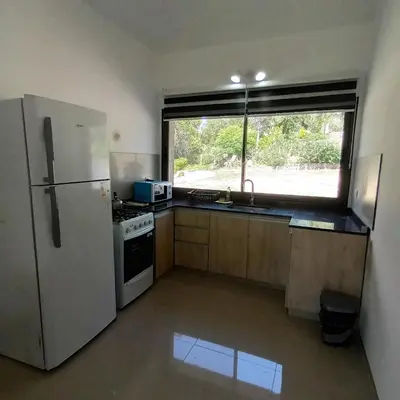 a kitchen with a white refrigerator and a window at Casa en Villa Carlos Paz con pileta y vista al Lago IG alquilervillacarlospaz in Villa Carlos Paz