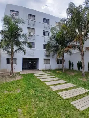 a white building with palm trees in front of it at Apartamento Alto Alberdi in Cordoba